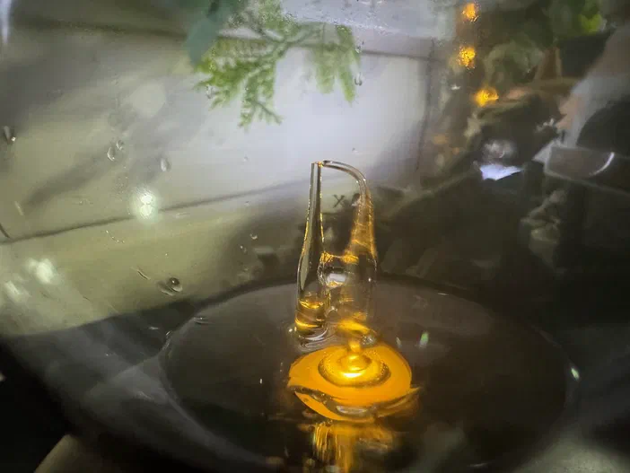Détail de l'ampoule d'un diffuseur à huiles essentielles montrant le mécanisme où l'air entre par un tube courbé et aspire l'huile qui remonte dans un autre tube pour être vaporisée.