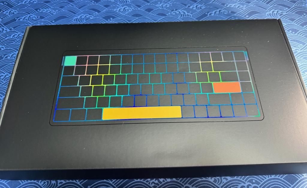 Extérieur du packaging du clavier. On notera que les couleurs changent avec l'orientation pour un rendu réel beaucoup plus sobre et classieux 0lwoLx
